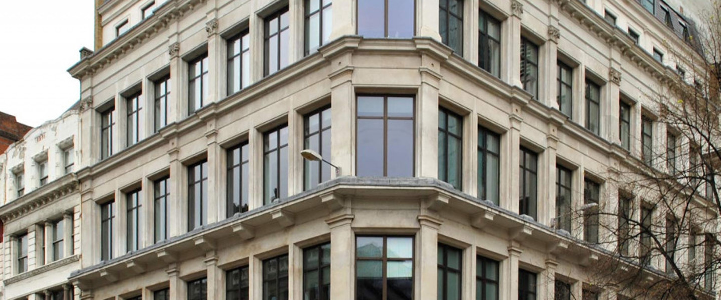 Modern kantoorgebouw met grote ramen en een hoekige vormgeving in een stedelijke omgeving.