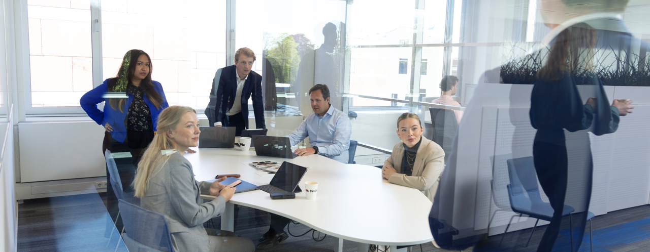 Een groep professionals in een vergaderruimte, gefocust op een presentatie en het uitwisselen van ideeën.