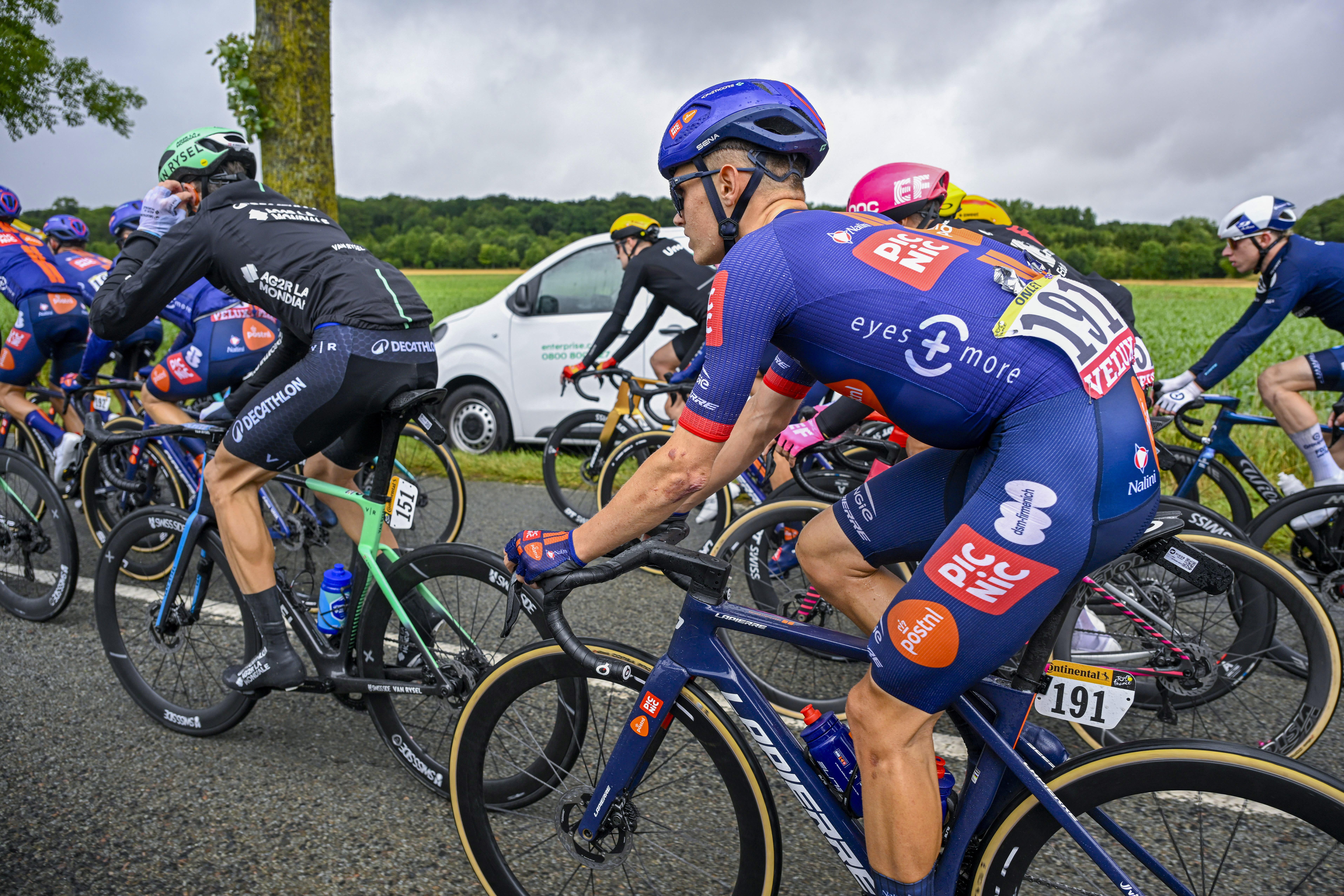 Racers cycling, with a focus on the rider in the center wearing number 192 and a bright blue team shirt.