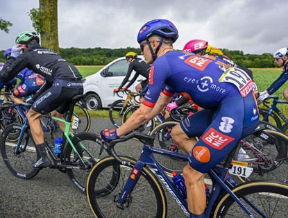 Racers cycling, with a focus on the rider in the center wearing number 192 and a bright blue team shirt.
