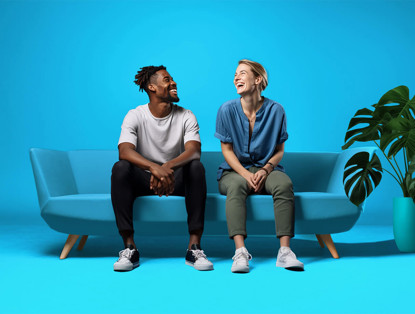 Twee mensen zitten op een lichtblauwe bank tegen een felblauwe achtergrond, met een groene plant rechts op de vloer.