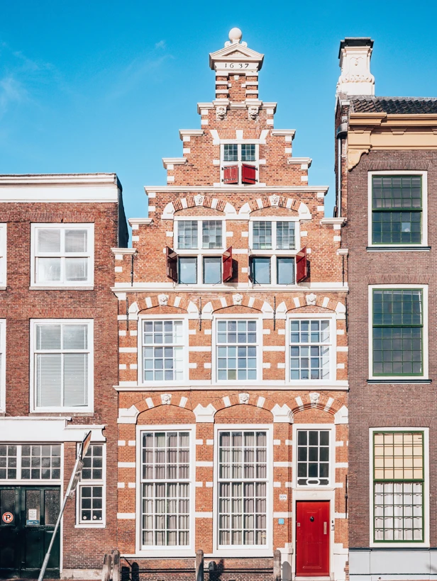 Red brick building with white details and an intricate facade design, situated between two other modern structures.