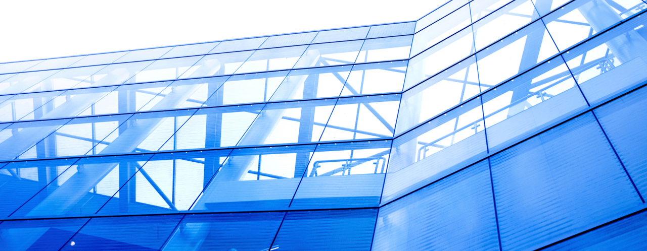 Blue glass facade of a modern office building with visible steel structure.
