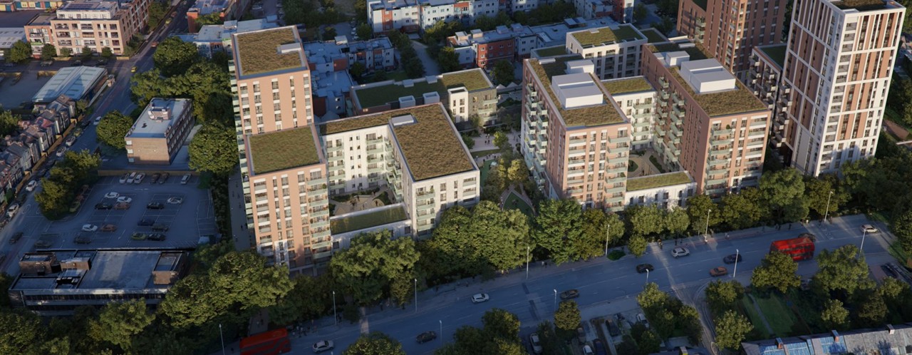 Luchtfoto van moderne appartementencomplexen met groene daken, omgeven door bomen en een straat vol voertuigen.