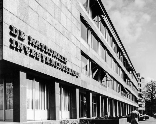 Hoofdingang van het kantoorgebouw van de Nationale Investeringsbank, met grote ramen en moderne zwart-witte architectuur.