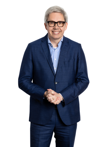 Toine in a blue suit stands with his arms crossed against a black background.