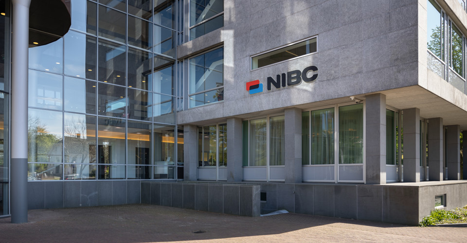 Main entrance of the NIBC office featuring large windows and the NIBC logo on the wall.