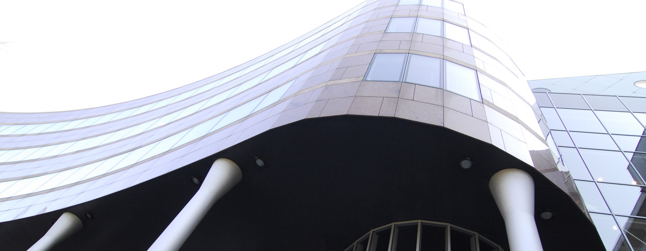 Modern kantoorgebouw met een golvende gevel en grote ramen, ondersteund door witte zuilen.